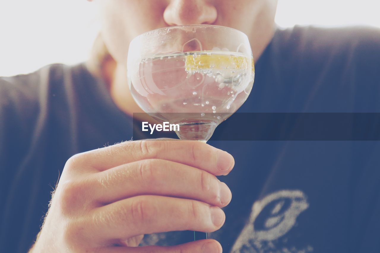 CLOSE-UP OF HAND HOLDING GLASS OF DRINK