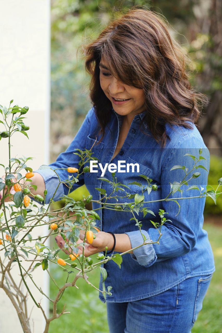 Happy hispanic woman looking at her home grown habanero peppers