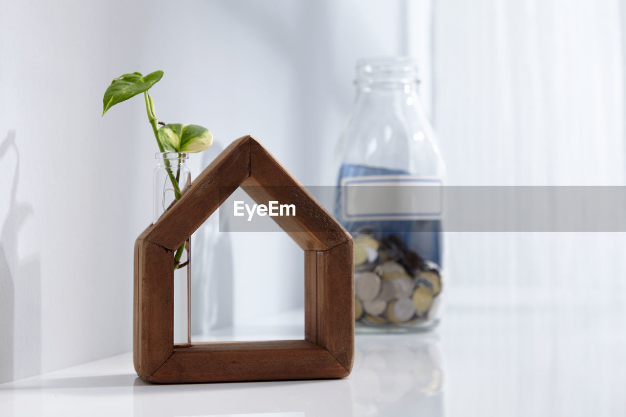 Hand made wooden house with saving jar near window