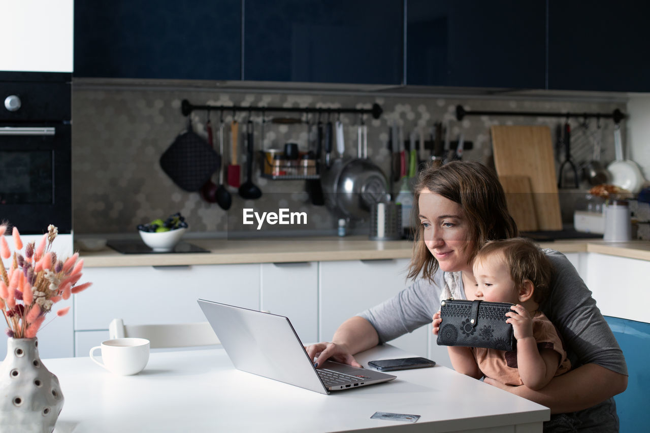 Smiling woman using laptop while sitting with girl