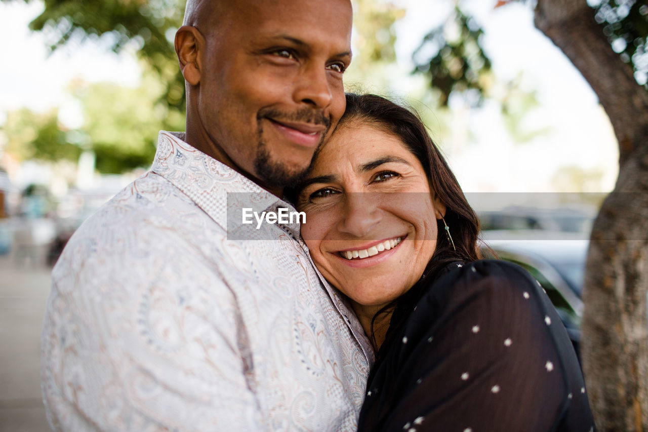 Multiracial late forties couple embracing on san diego sidewalk