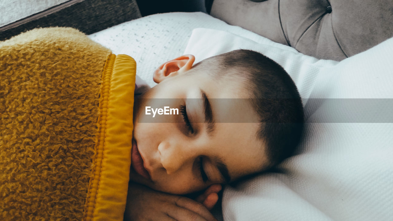 Close-up of boy sleeping on bed at home