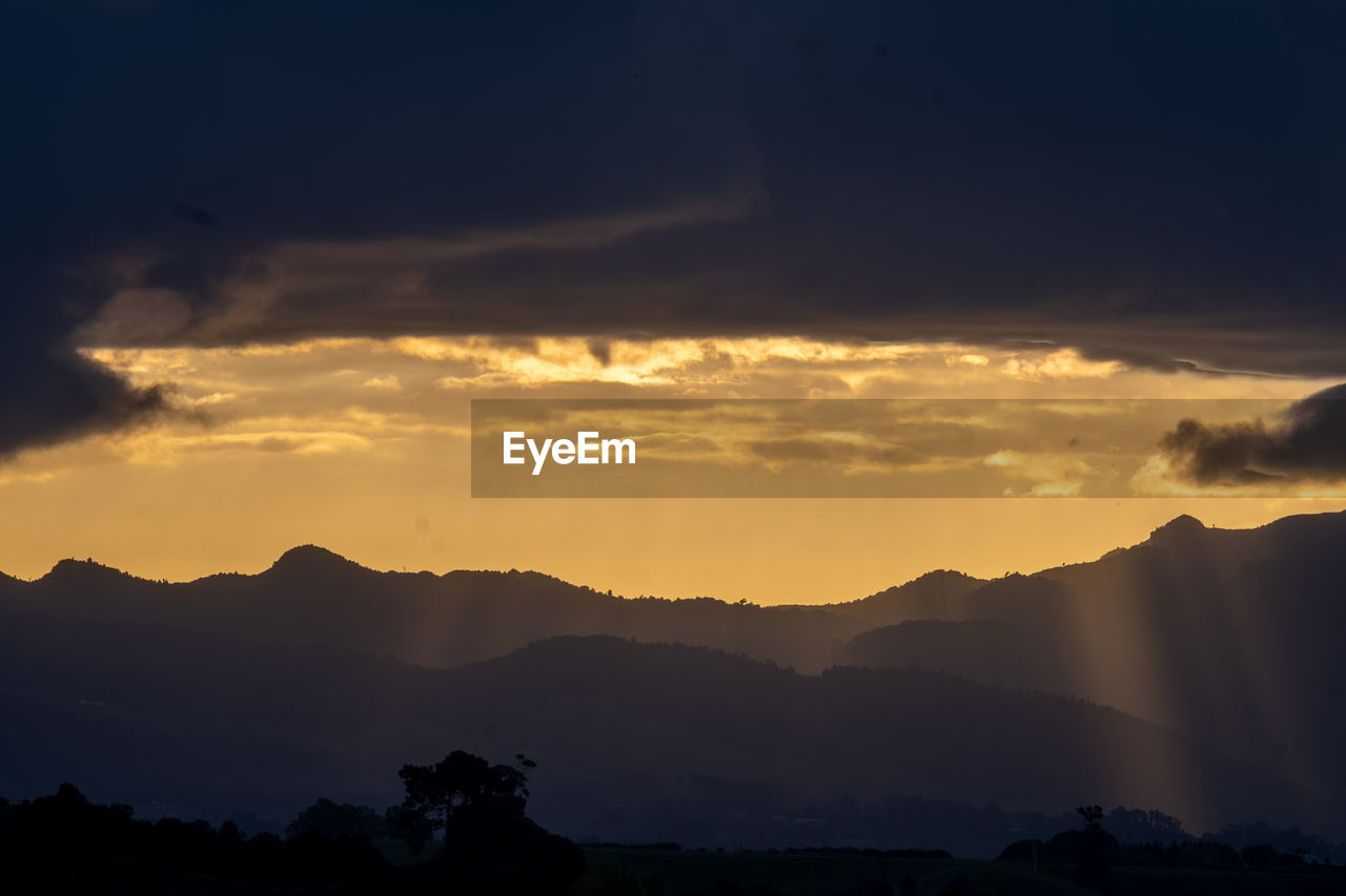 SCENIC VIEW OF SILHOUETTE MOUNTAINS AGAINST DRAMATIC SKY