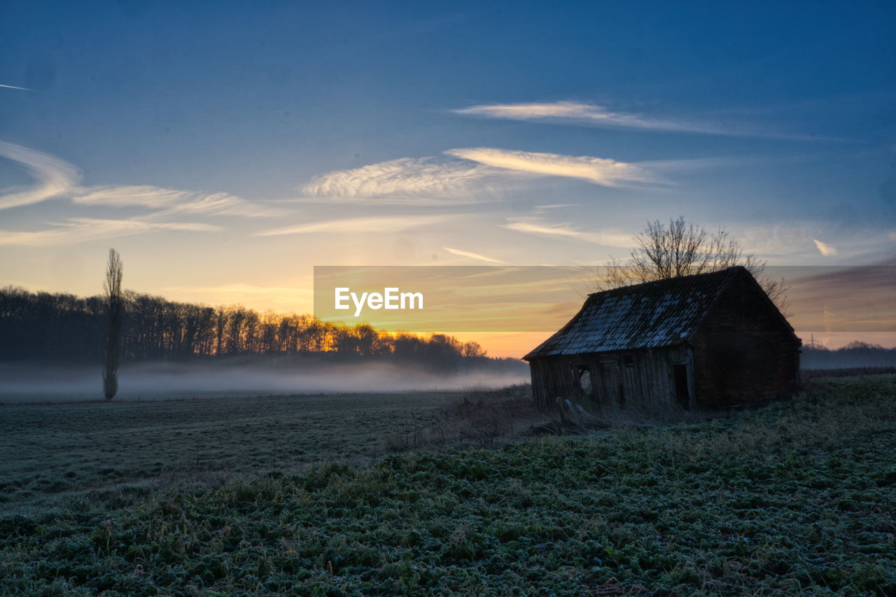 House on field against sky during sunrise