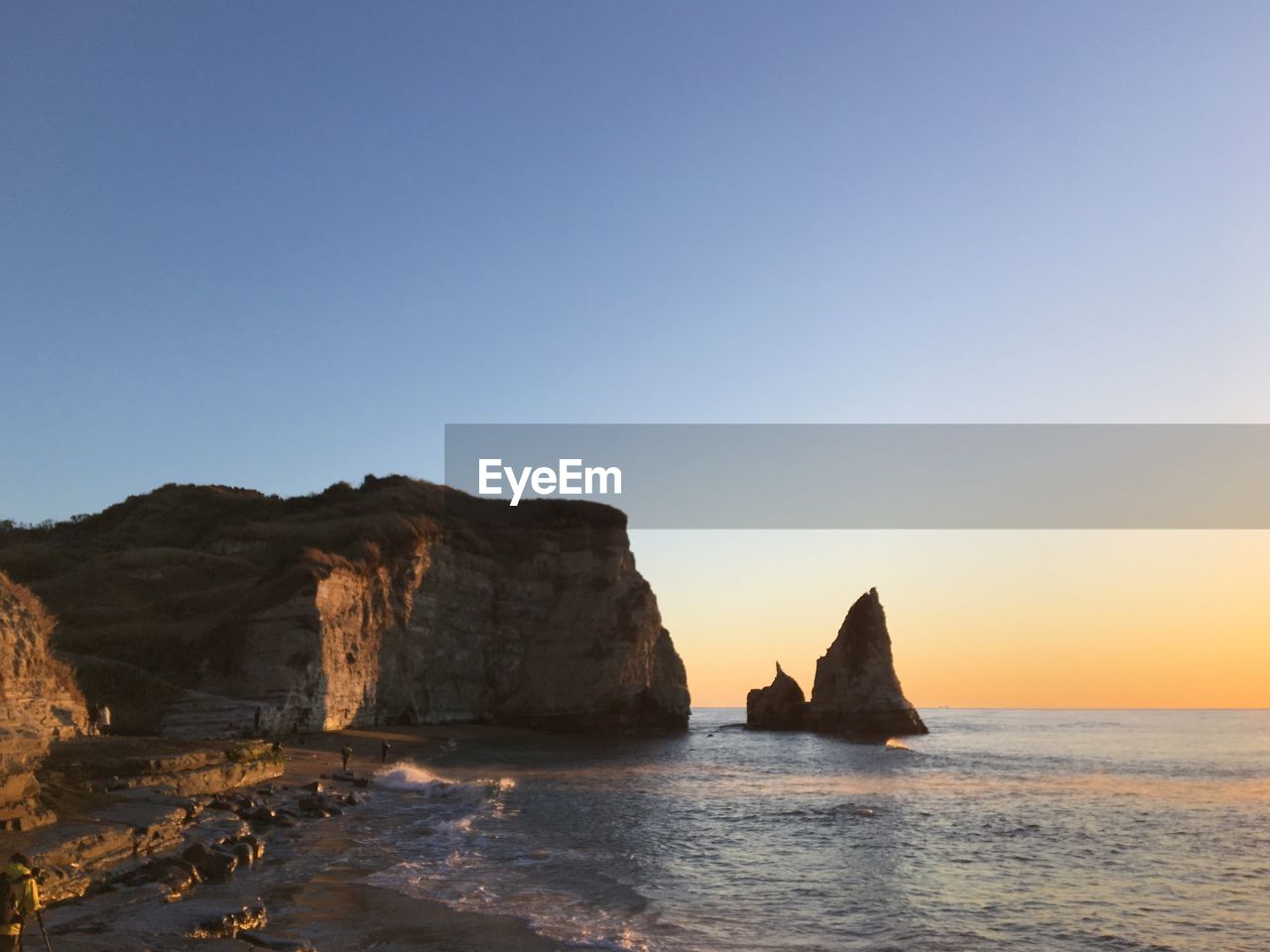 Rock formations in sea against clear sky