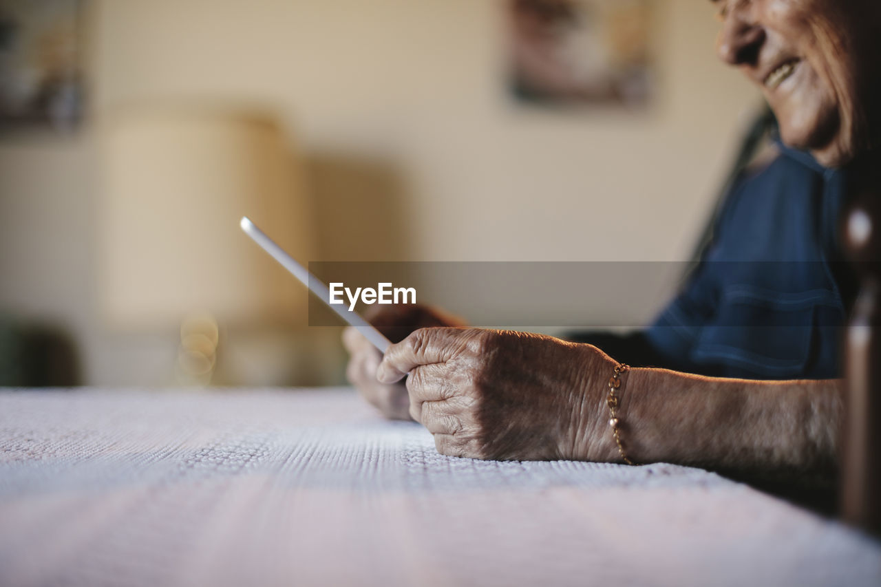 Cropped image of senior man holding tablet computer at table