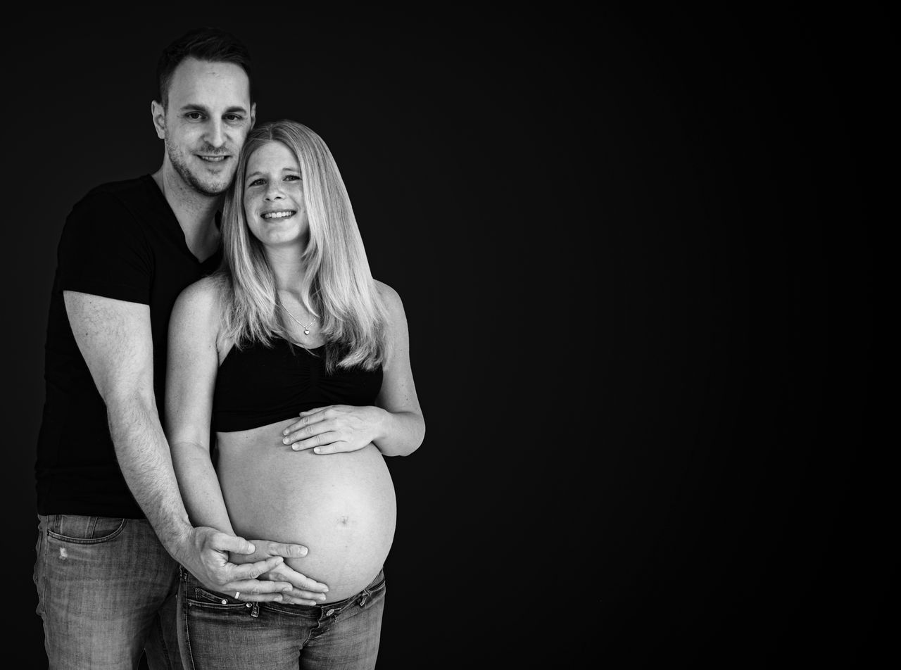 PORTRAIT OF A SMILING COUPLE AGAINST BLACK BACKGROUND