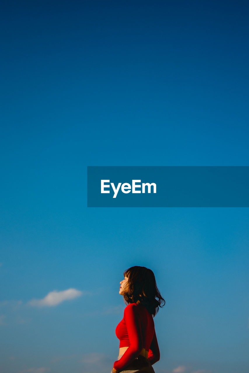 Rear view of woman standing against blue sky