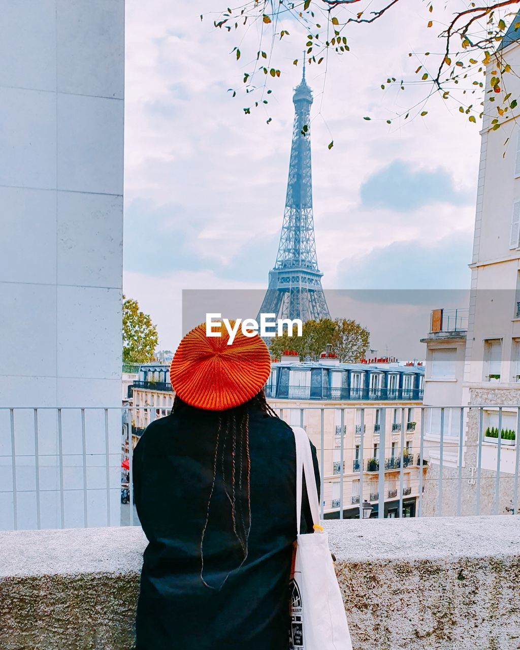 Rear view of woman standing by building against sky