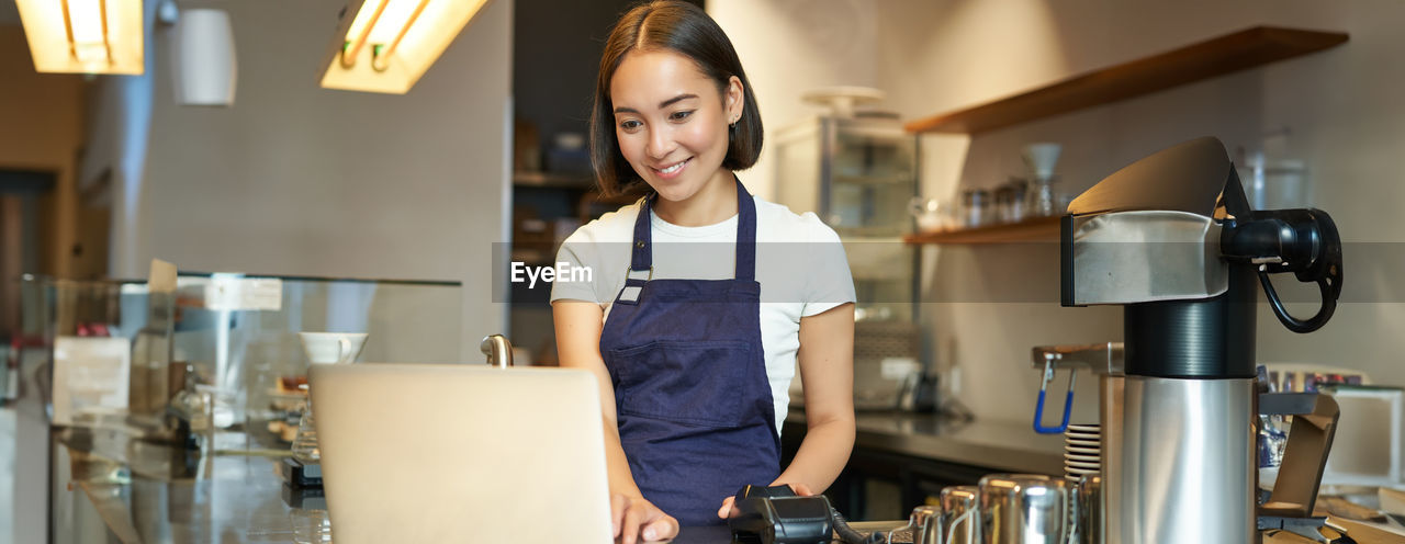 portrait of young woman looking at smart phone in cafe