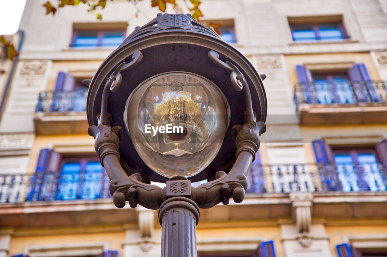 LOW ANGLE VIEW OF ELECTRIC LAMP AGAINST BUILDING