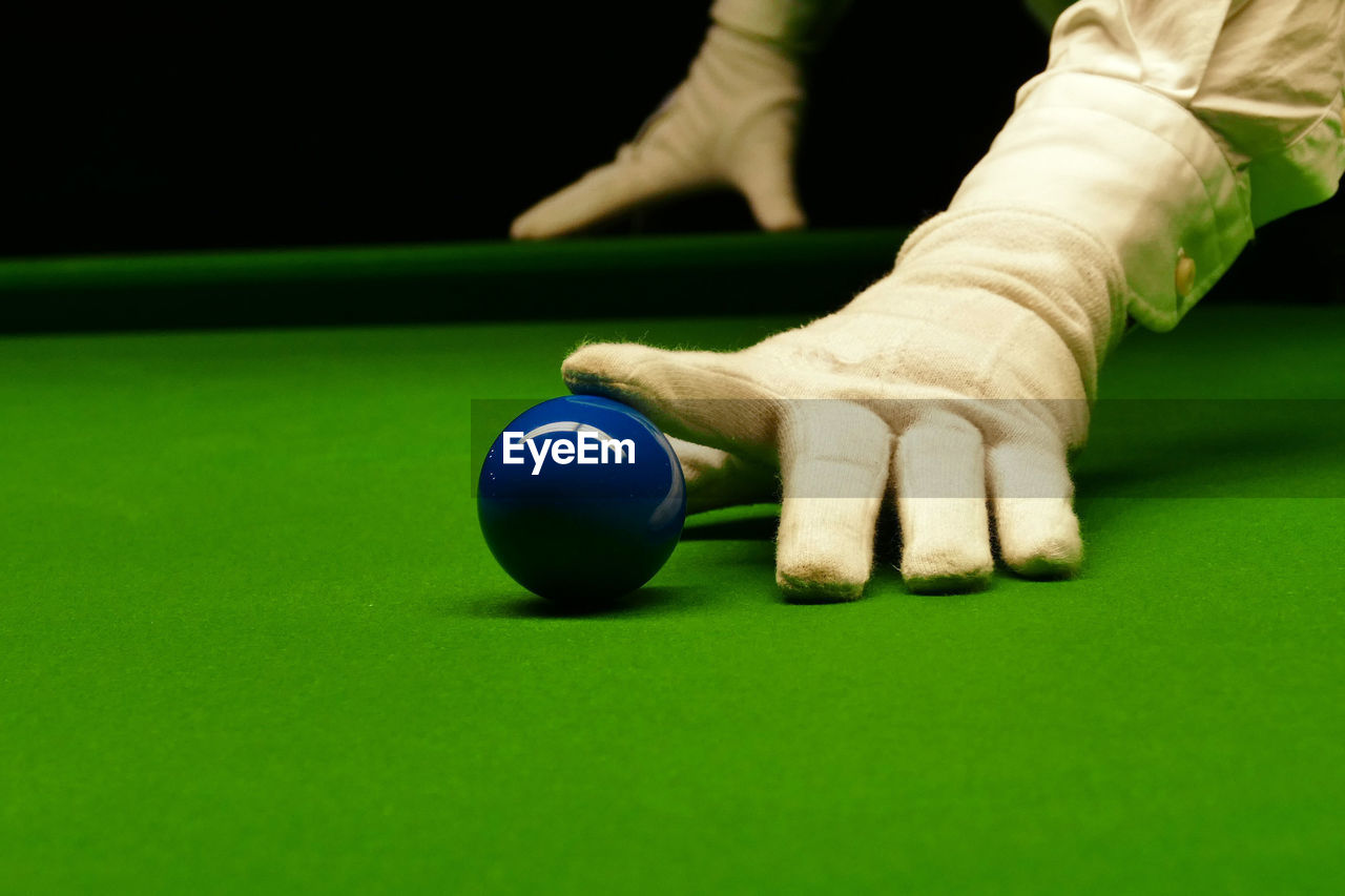 Cropped hands touching ball on pool table
