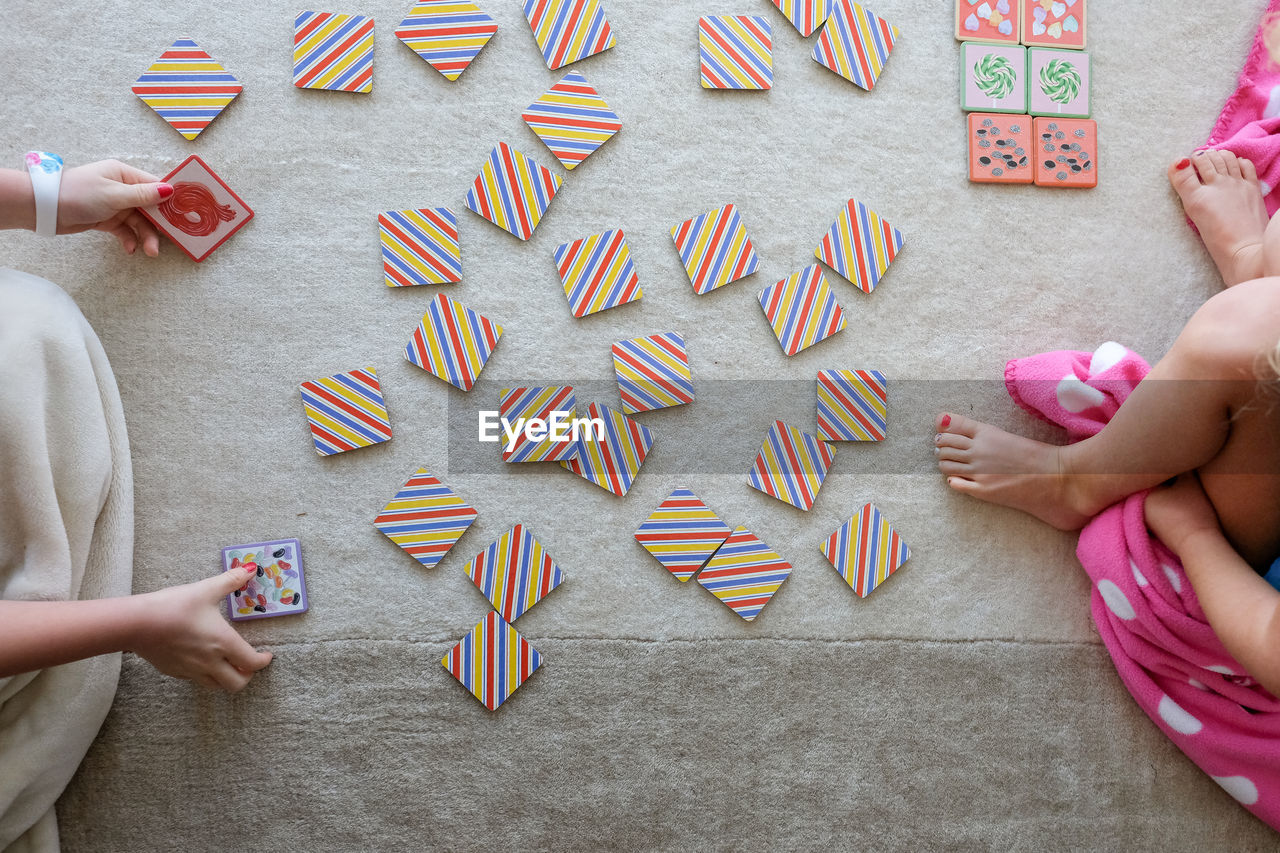 Overhead view of kids playing card game sitting on a rug