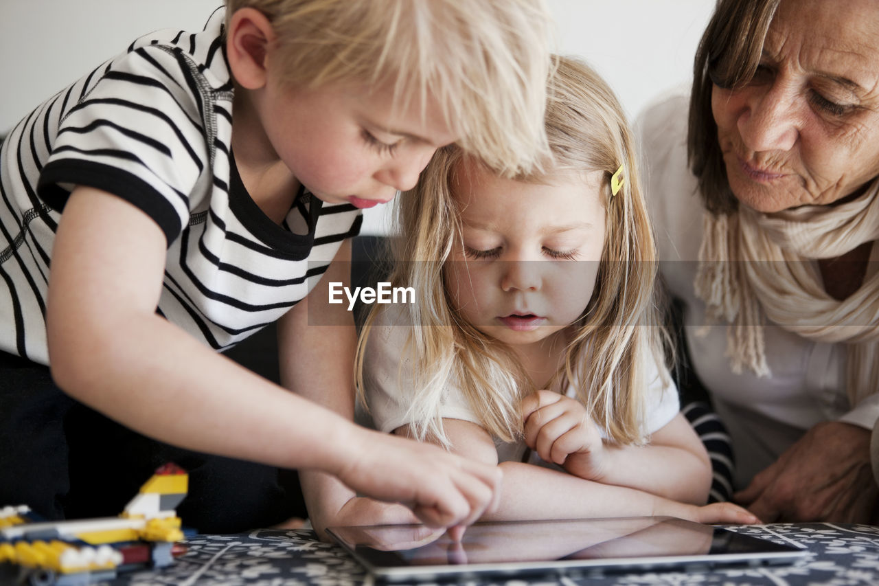 Grandmother with grandchildren using digital tablet