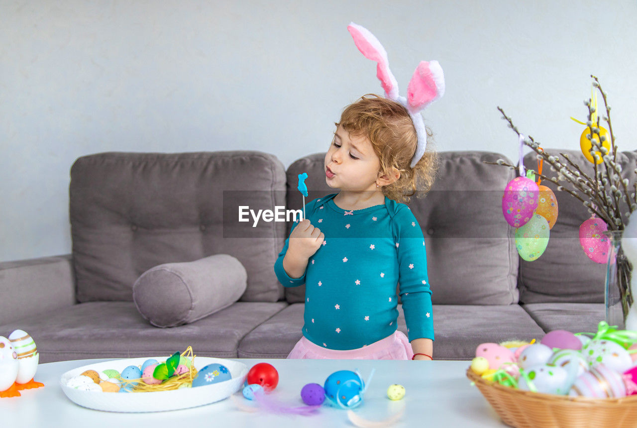 easter, child, childhood, easter egg, celebration, toddler, indoors, one person, egg, furniture, birthday cake, domestic room, sitting, cute, sweet food, clothing, food, holiday, innocence, person, multi colored, decoration, party, women, fun, sofa, food and drink, sweet, home interior, living room, lifestyles, human face, baby, easter bunny, event, emotion, female, nature, domestic life, tradition, toy, front view, plant, table, animal