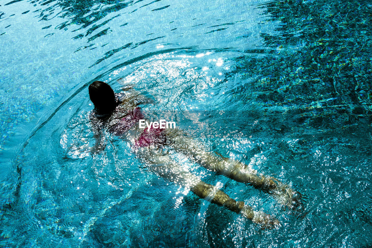 Rear view full length of woman wearing bikini swimming in pool