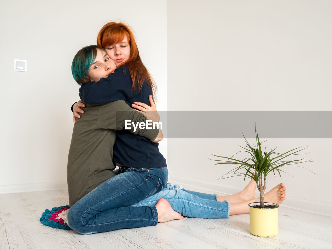 Portrait of woman embracing girlfriend kneeling at home