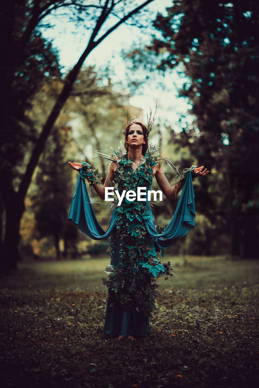 WOMAN STANDING BY TREE