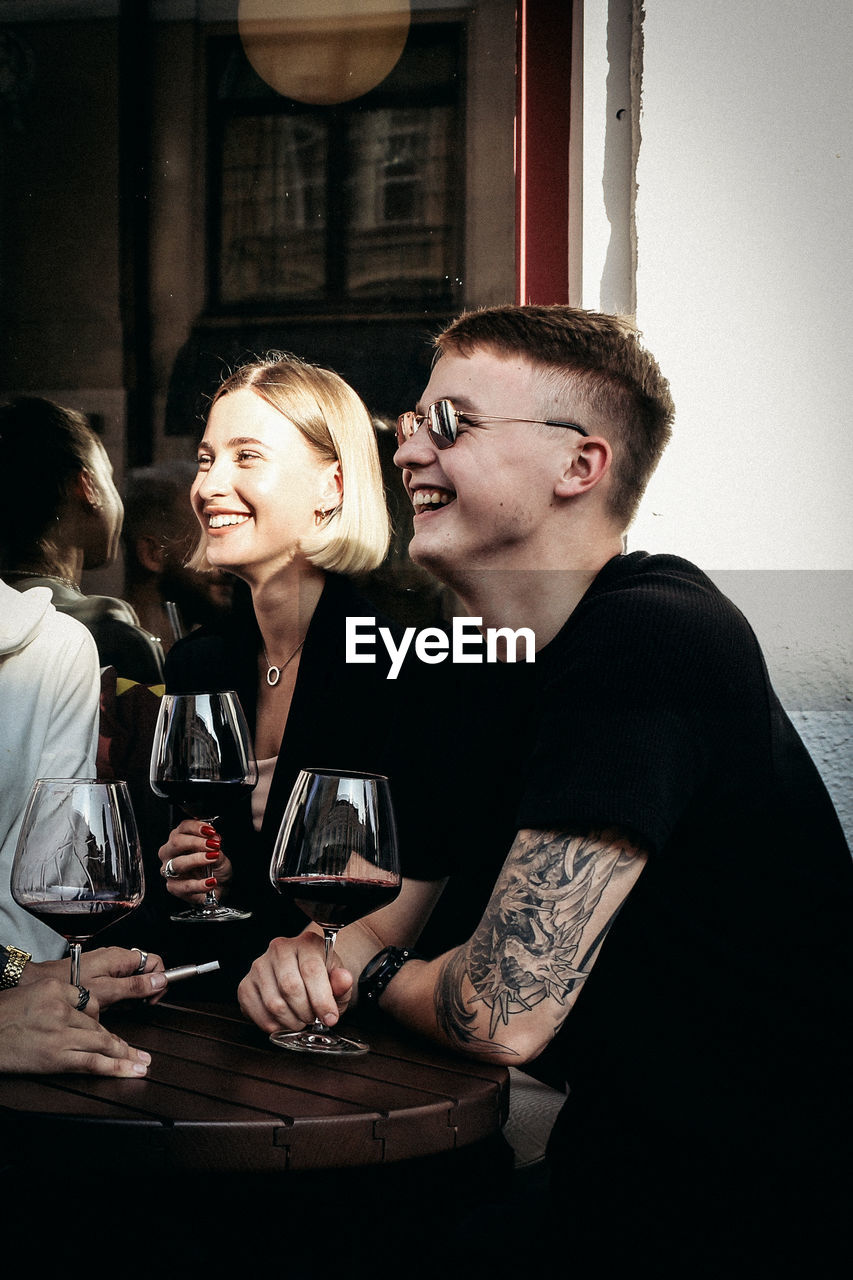 Young couple holding wineglass sitting at restaurant