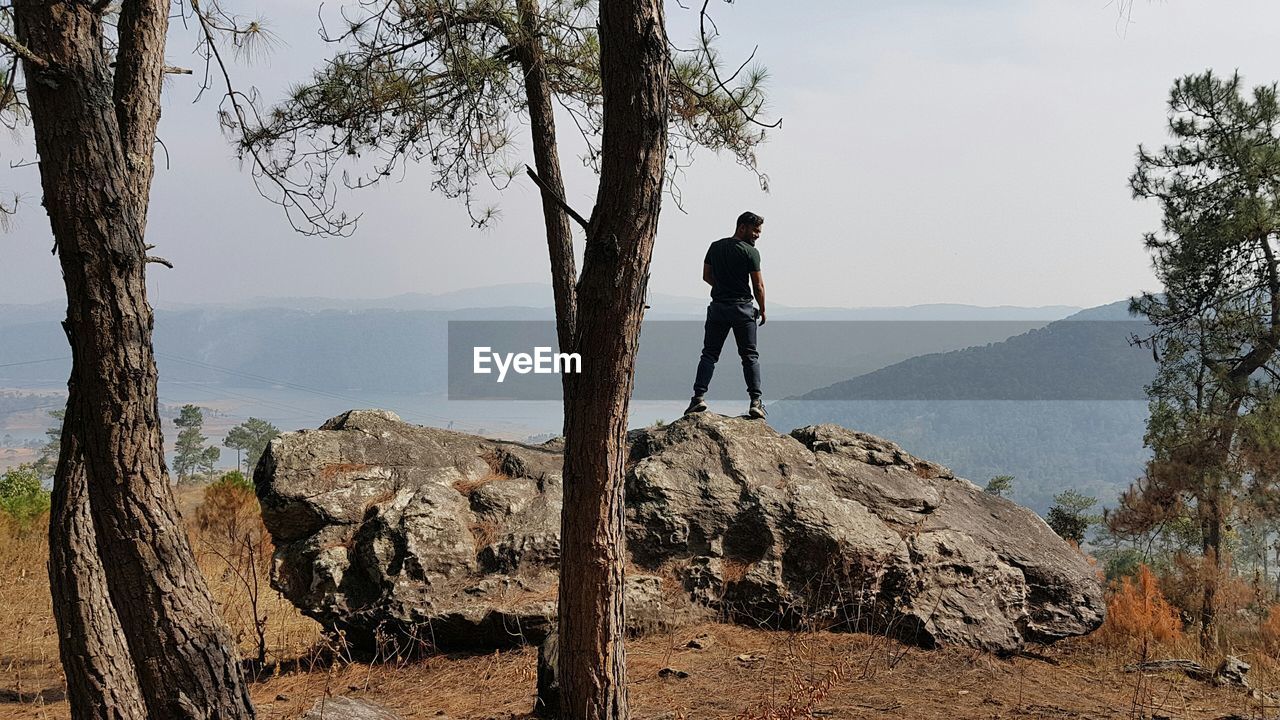 Rear view of man standing on rock against mountains