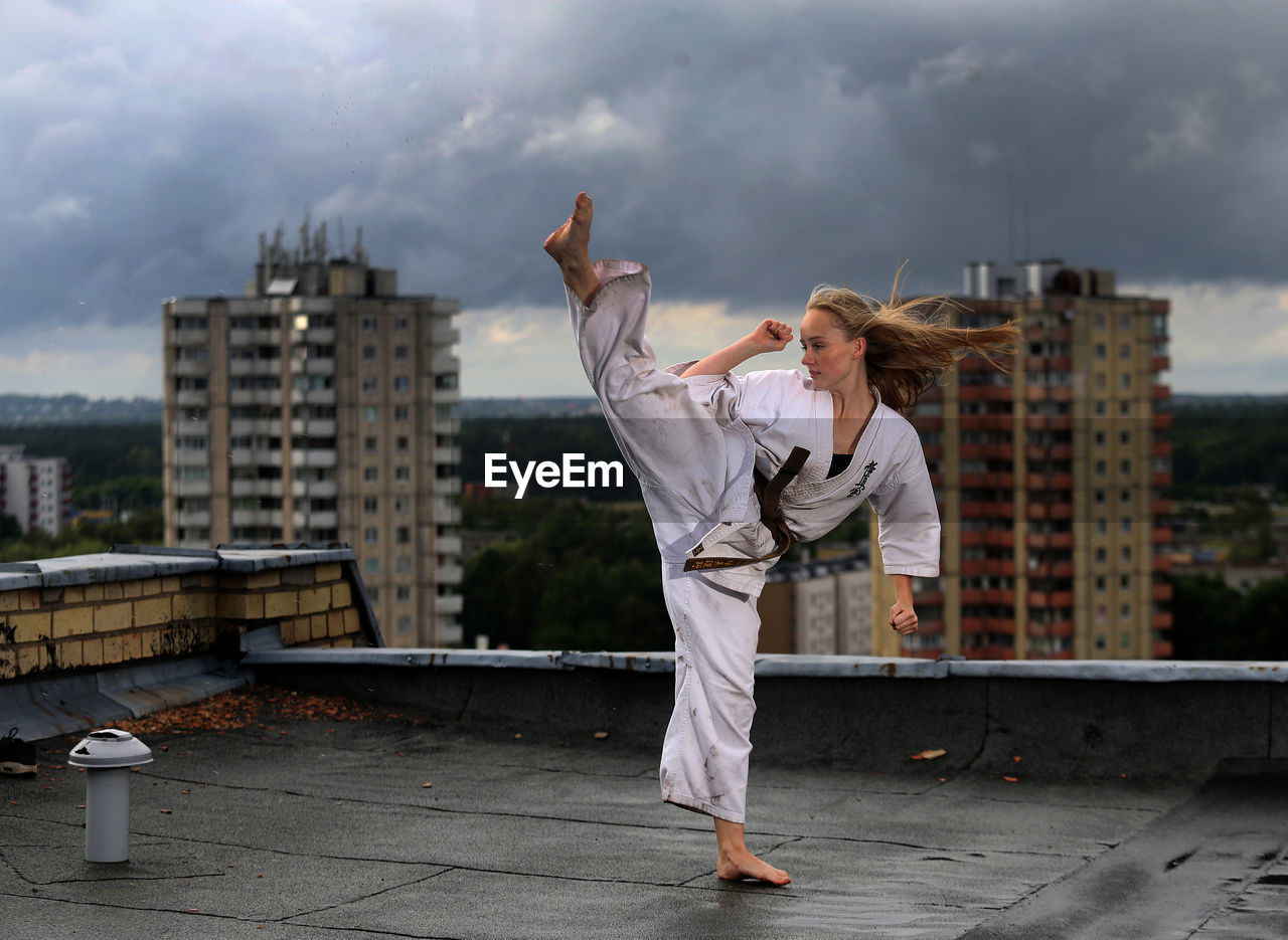 Woman doing karate on rooftop in city