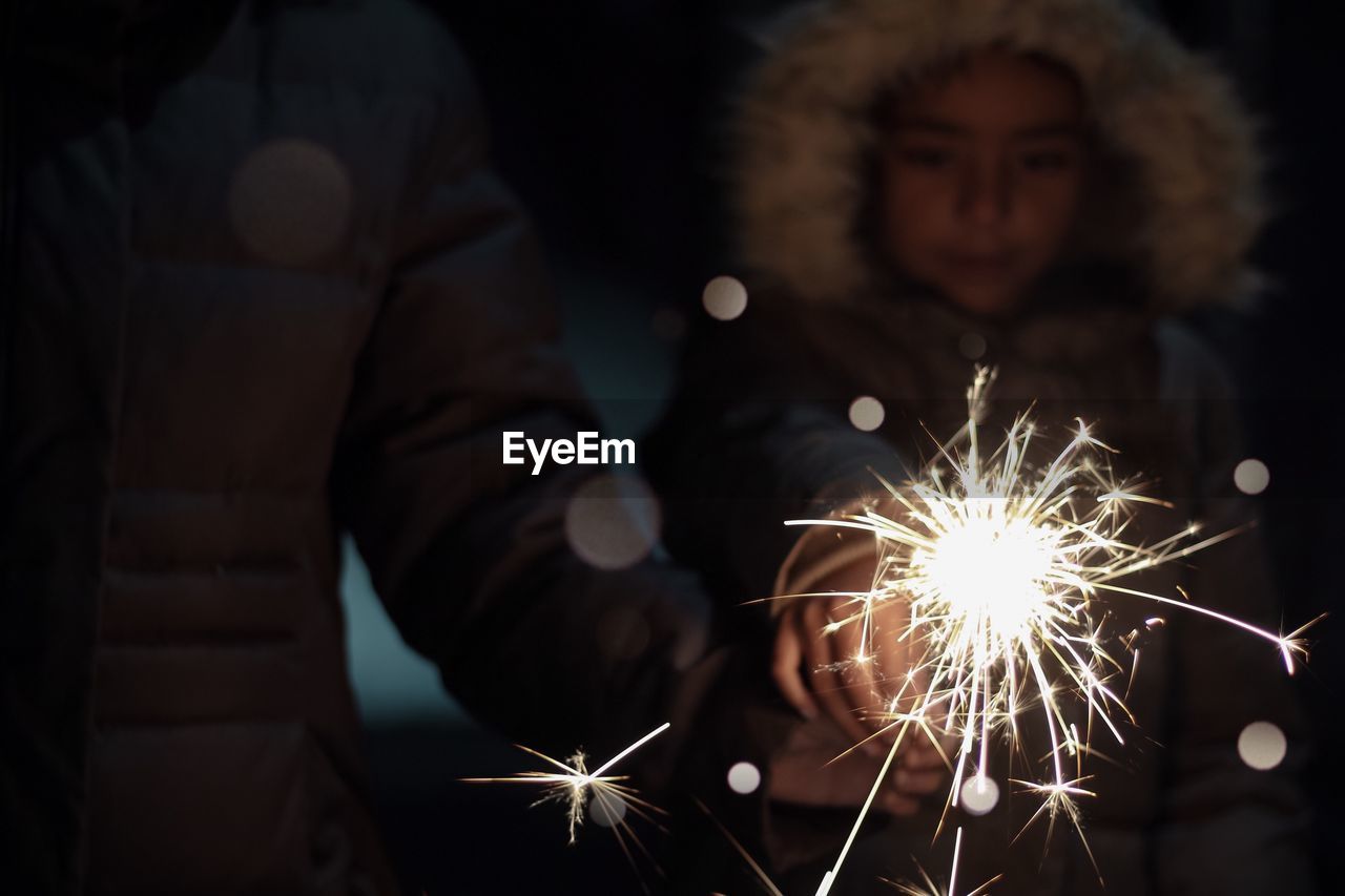 Girl with father holding illuminated sparkler at night