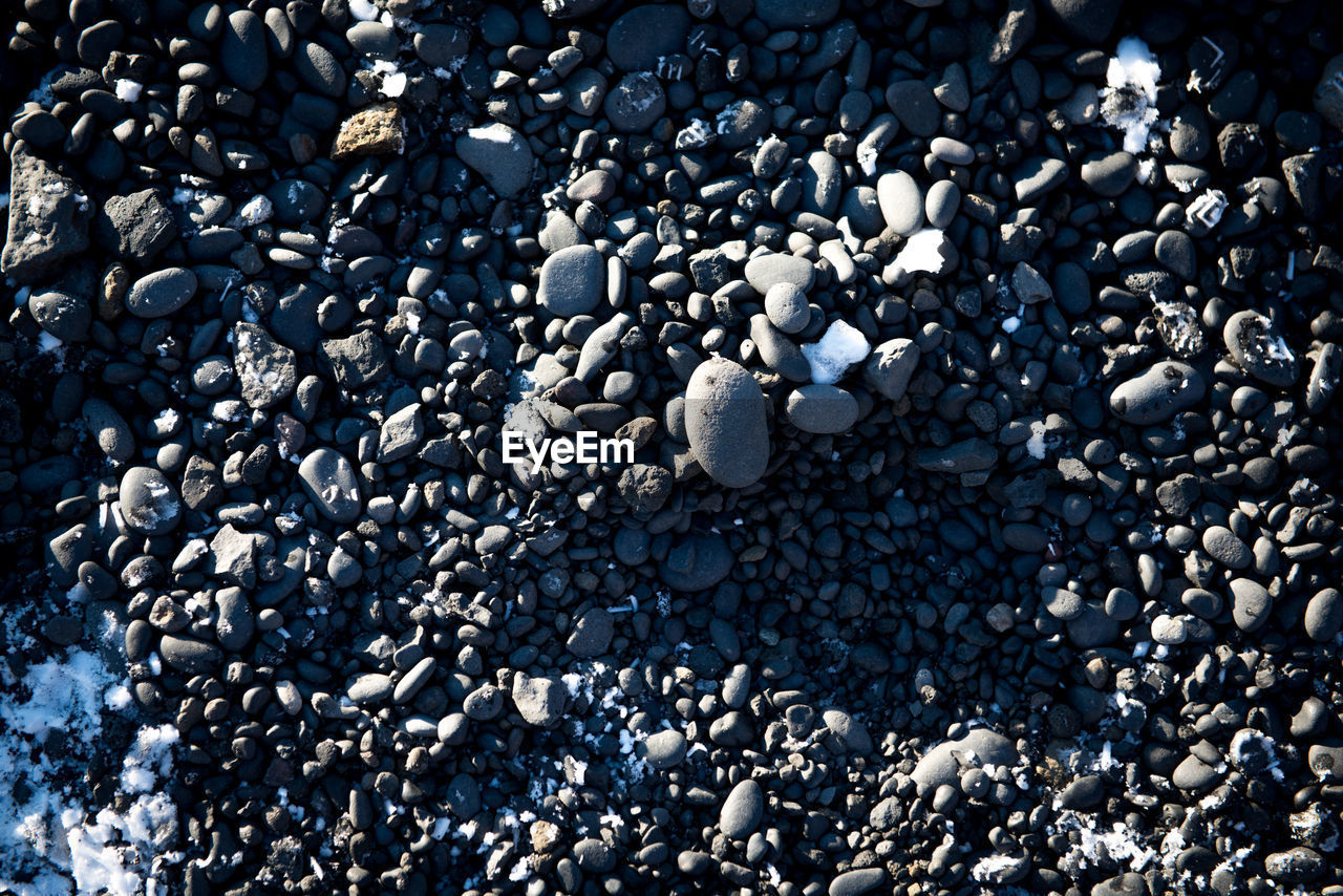 HIGH ANGLE VIEW OF STONES ON PEBBLE BEACH