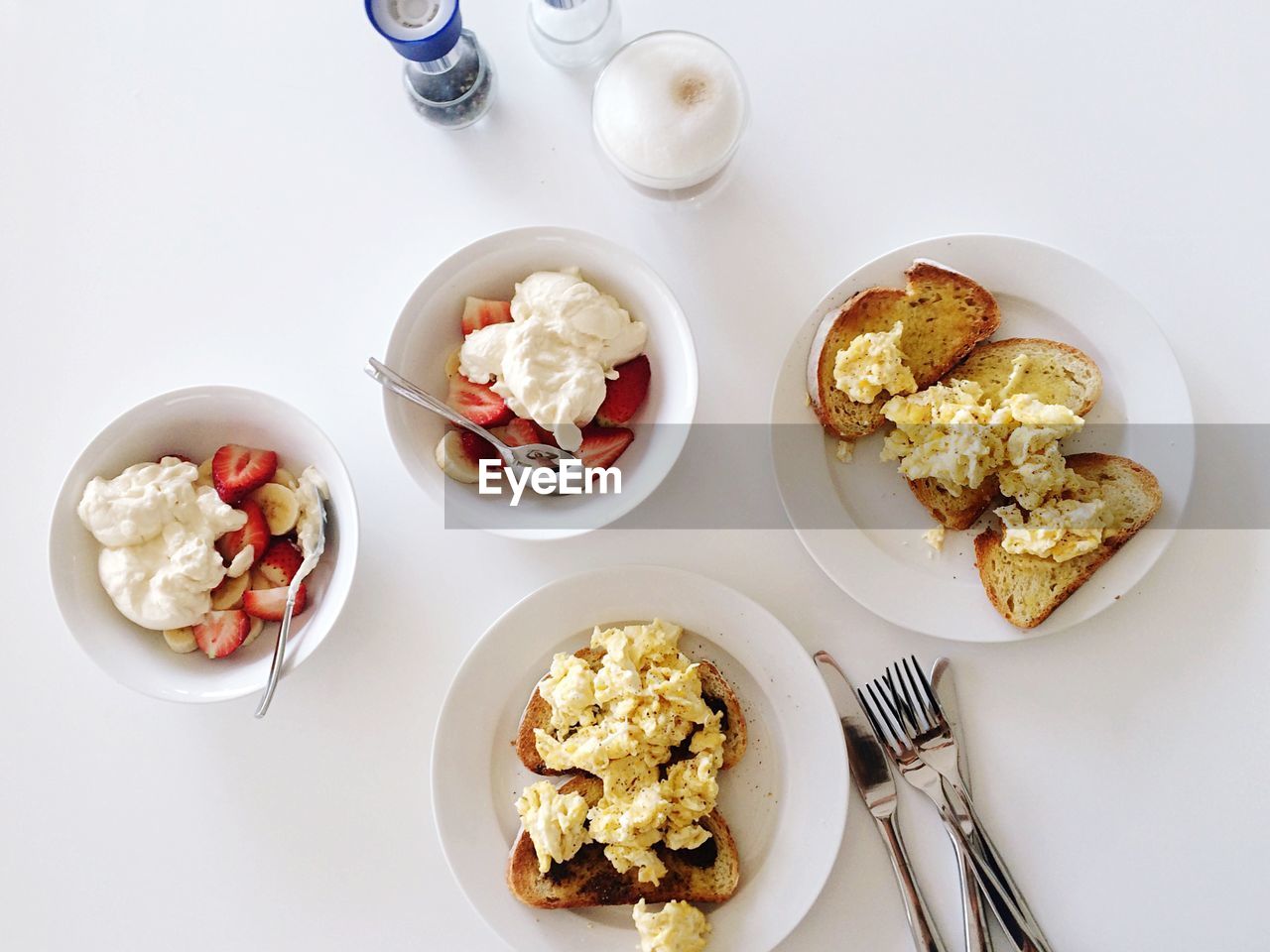 High angle view of scrambled eggs on toast and yogurt with fruits served on table