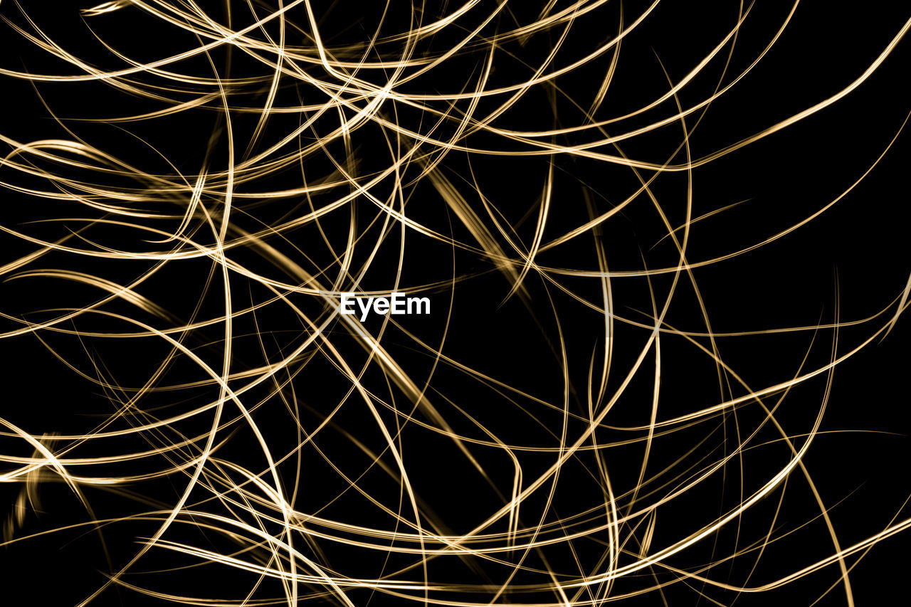Close-up of curved, golden light trails on a black background