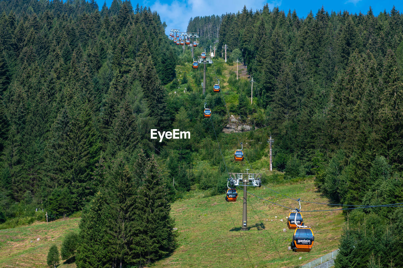 High angle view of overhead cables cars moving over green landscape during sunny day