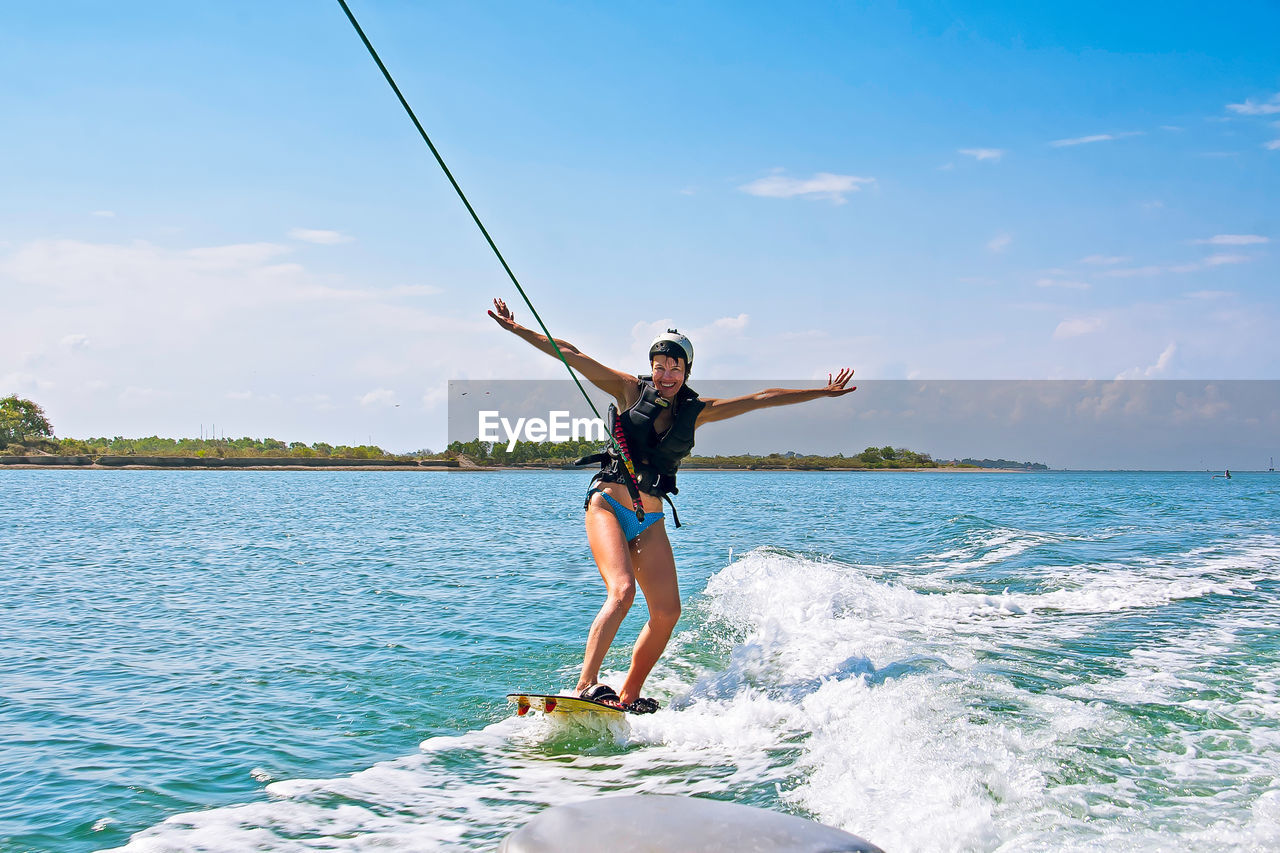 Woman kitebaording in sea against sky