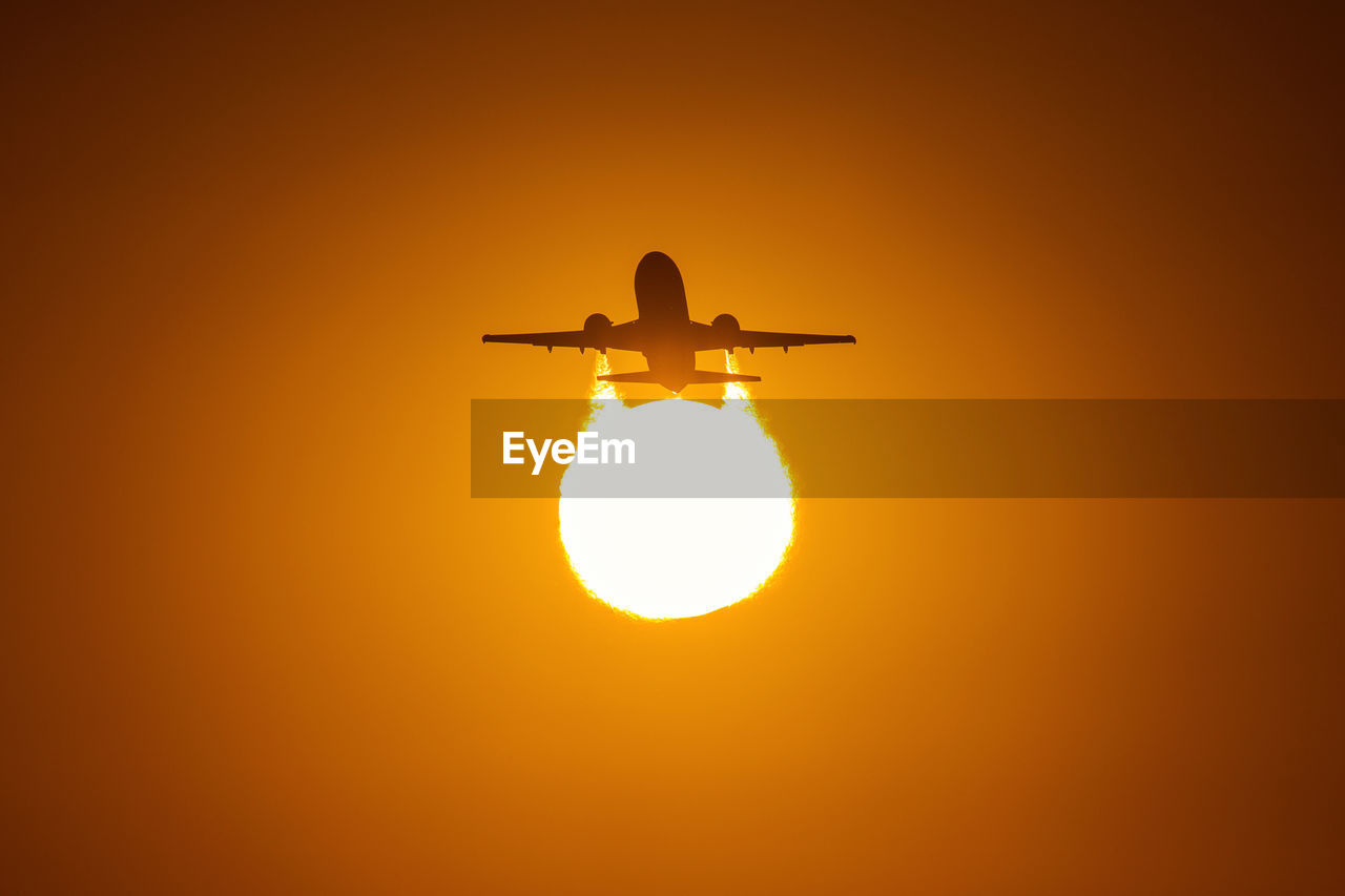LOW ANGLE VIEW OF SILHOUETTE AIRPLANE AGAINST ORANGE SKY