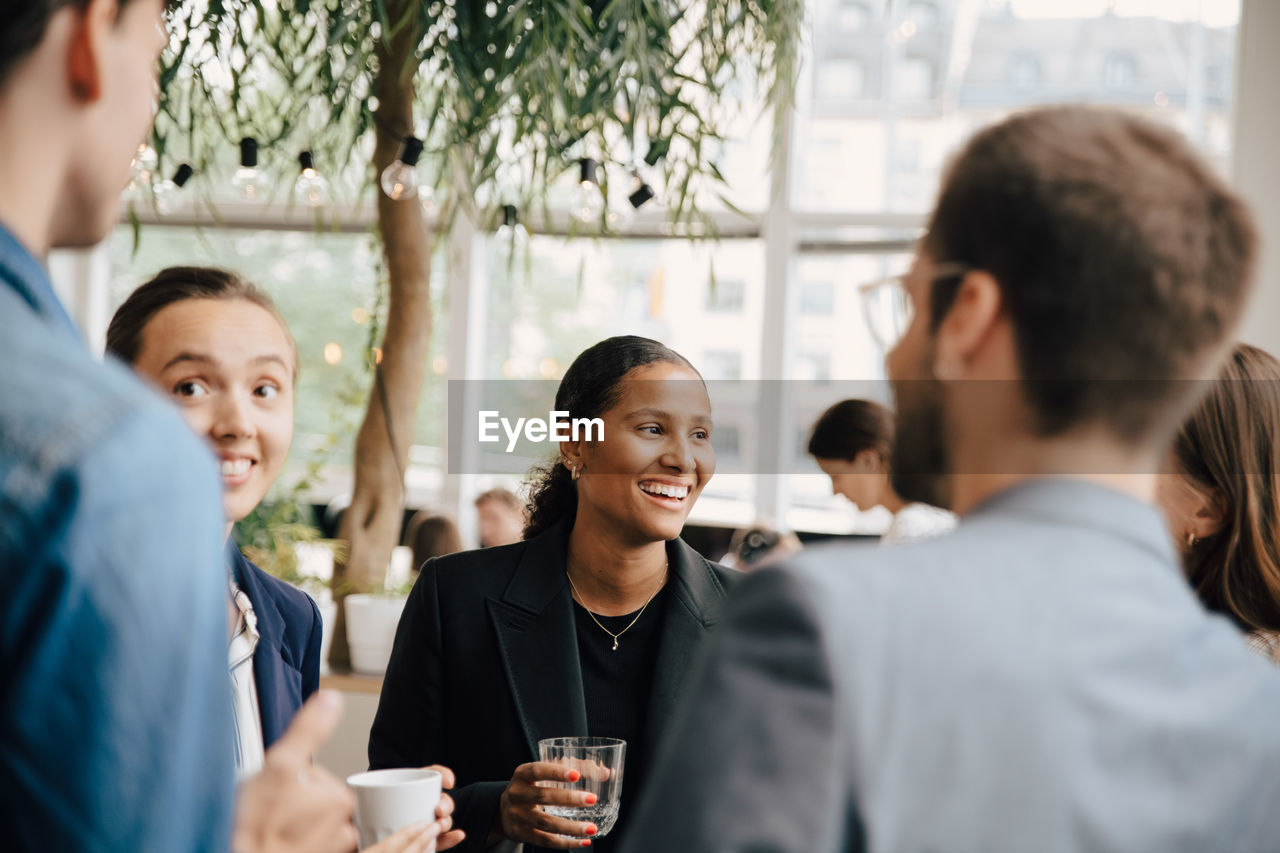 Smiling male and female colleagues discussing during coffee break