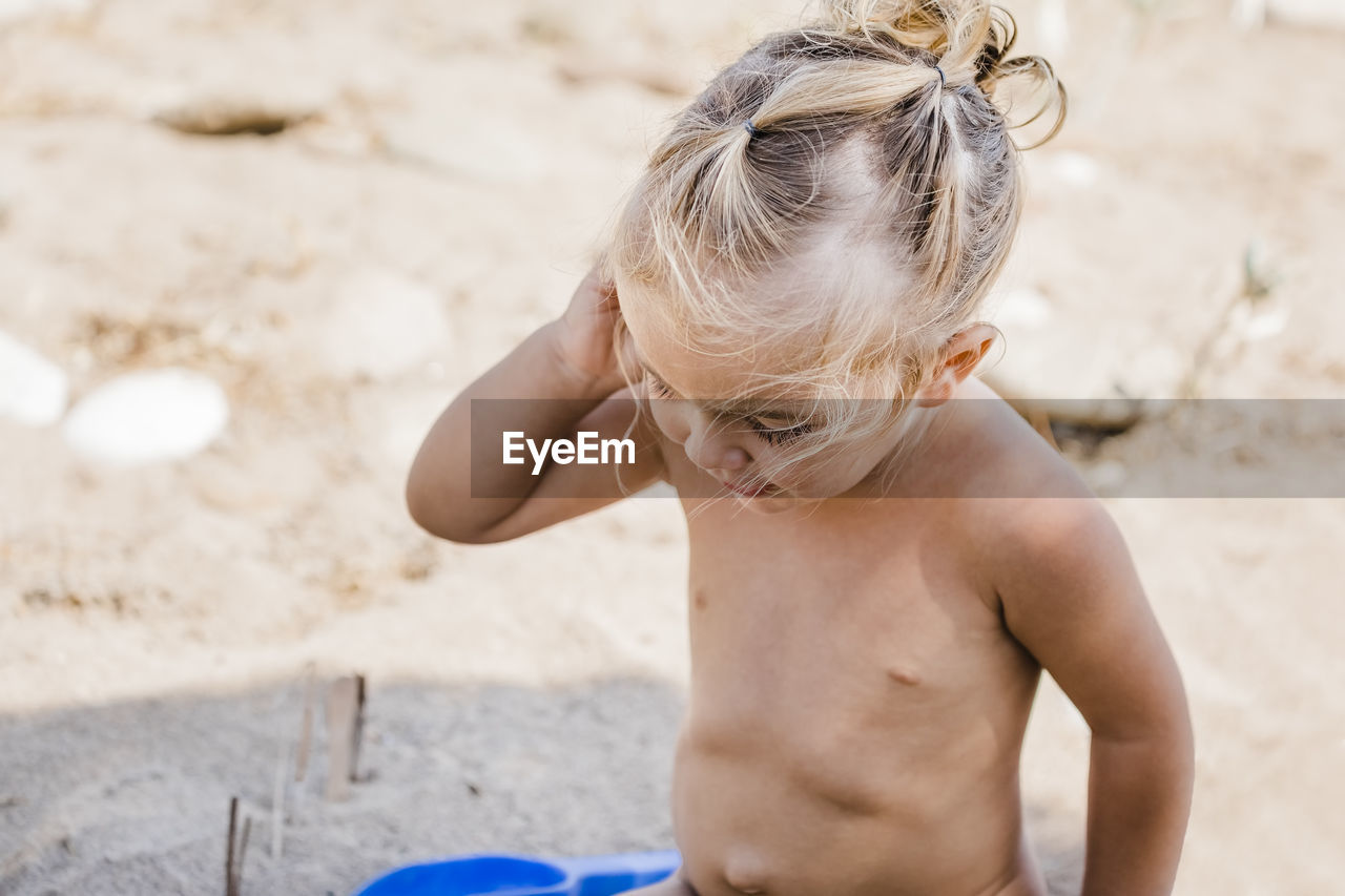 Shirtless girl standing on sand at beach