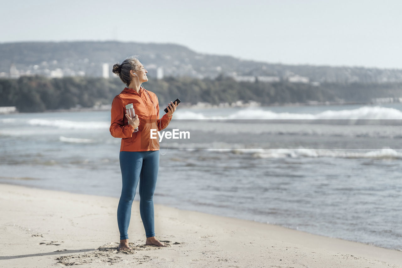 Mature woman standing on sand at beach