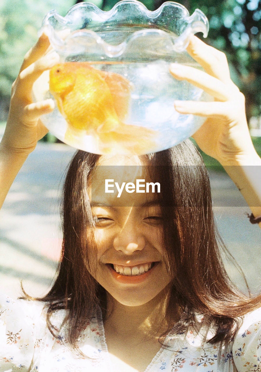 CLOSE-UP PORTRAIT OF A SMILING YOUNG WOMAN HOLDING A OUTDOORS