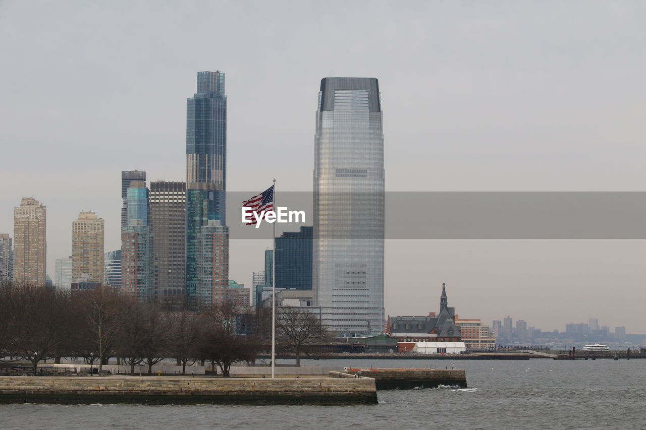 architecture, skyline, city, built structure, building exterior, office building exterior, skyscraper, building, landscape, urban skyline, sky, water, cityscape, tower block, downtown, travel destinations, horizon, office, nature, urban area, flag, downtown district, patriotism, waterfront, ship, residential district, tower, travel, no people, landmark, river, business, city life, harbor, outdoors, transportation, coast, vehicle, tourism, nautical vessel, financial district, day, environment