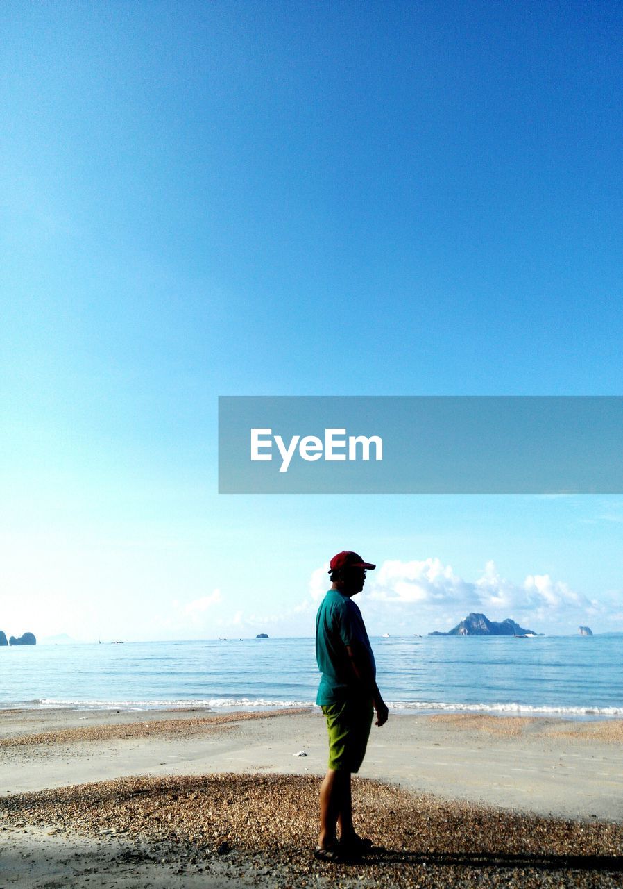 Side view of man standing on shore against sky