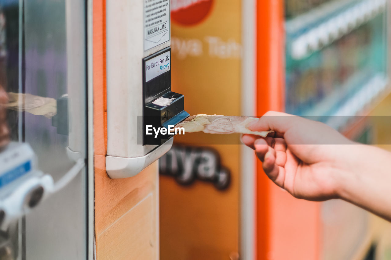 Close-up of hand holding paper currency at atm machine