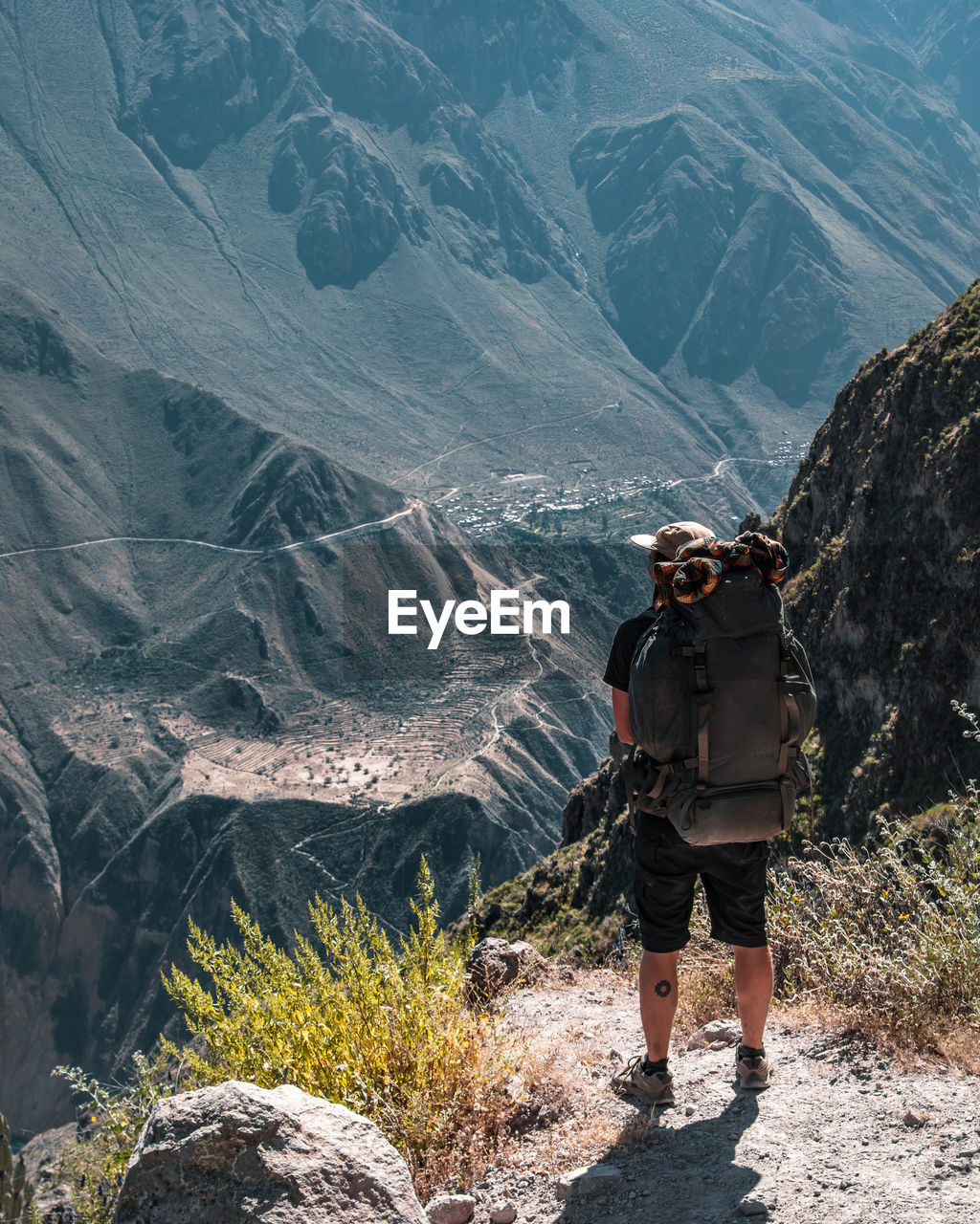 Rear view of hiker with backpack standing on mountain