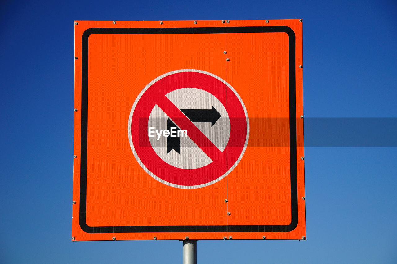 Close-up of warning sign against clear blue sky