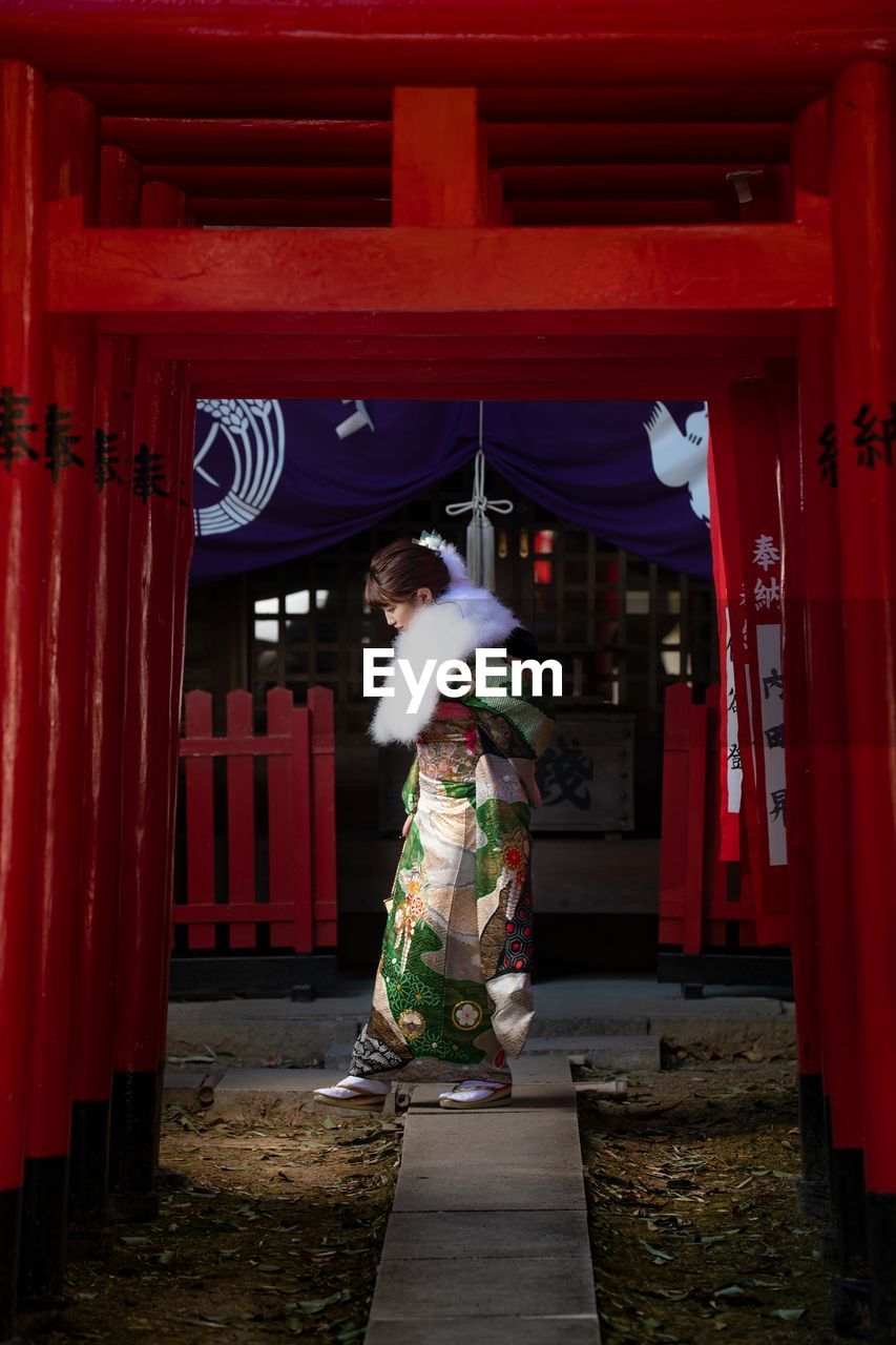 WOMAN STANDING BY RED BUILDING