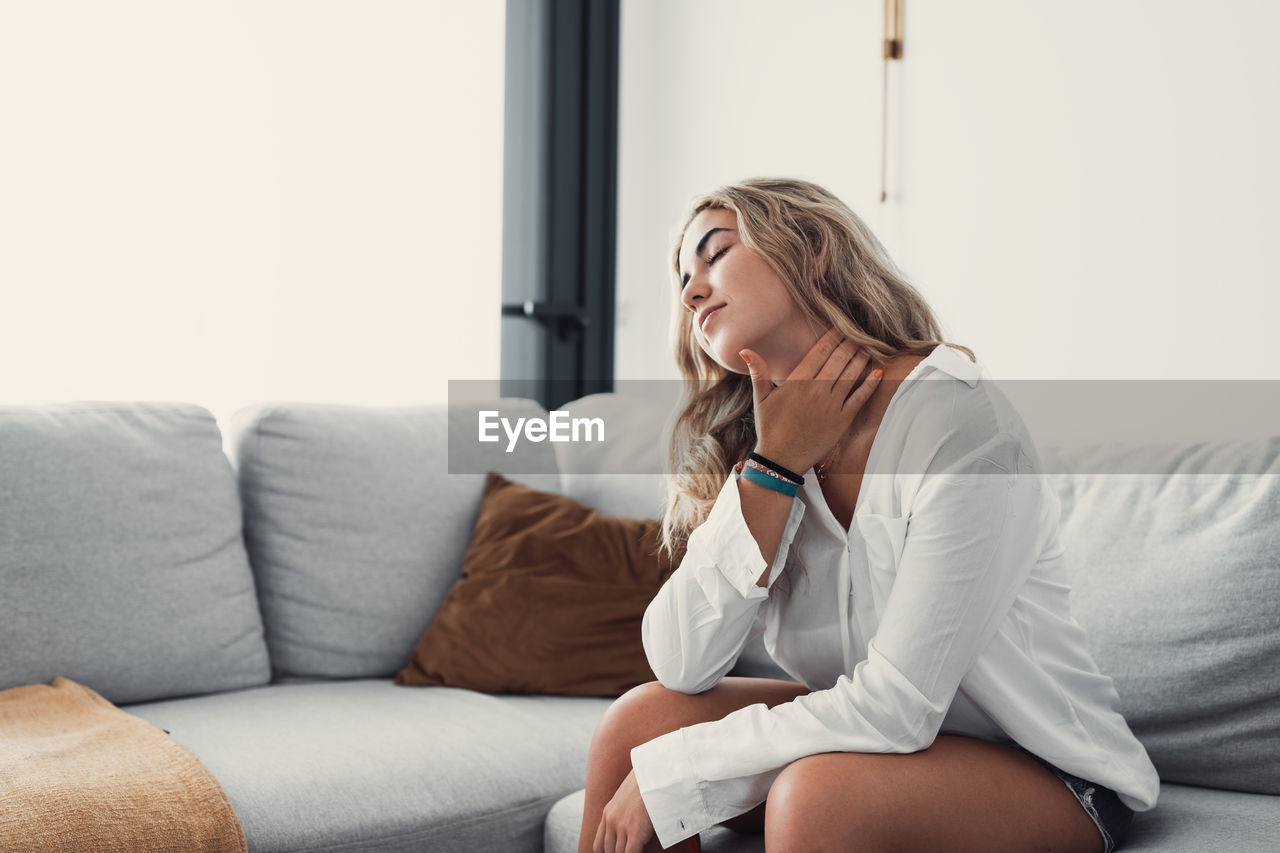 young woman using mobile phone while lying on bed at home