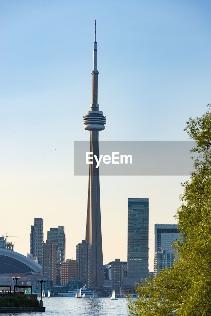 Cn tower by river against clear sky in city