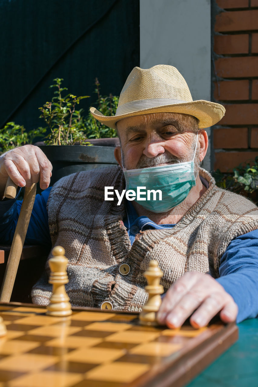 Senior man playing chess in yard