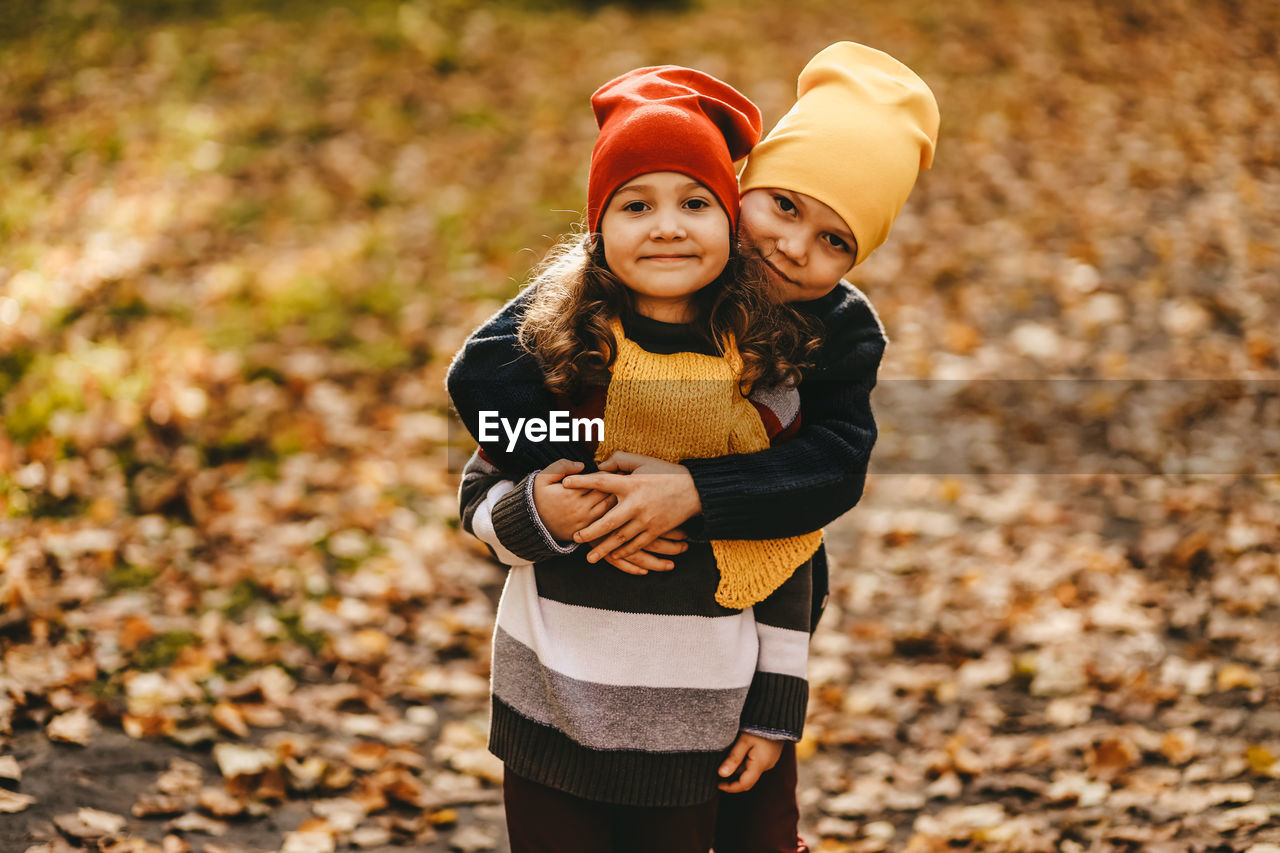 Happy cheerful children in warm clothes have fun walking running in autumn park playing with leaves