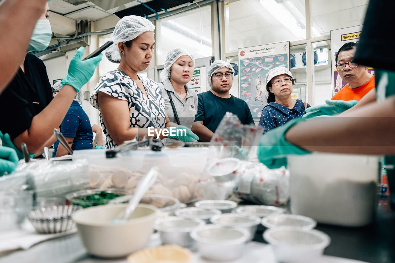 GROUP OF PEOPLE WORKING IN KITCHEN AT HOME