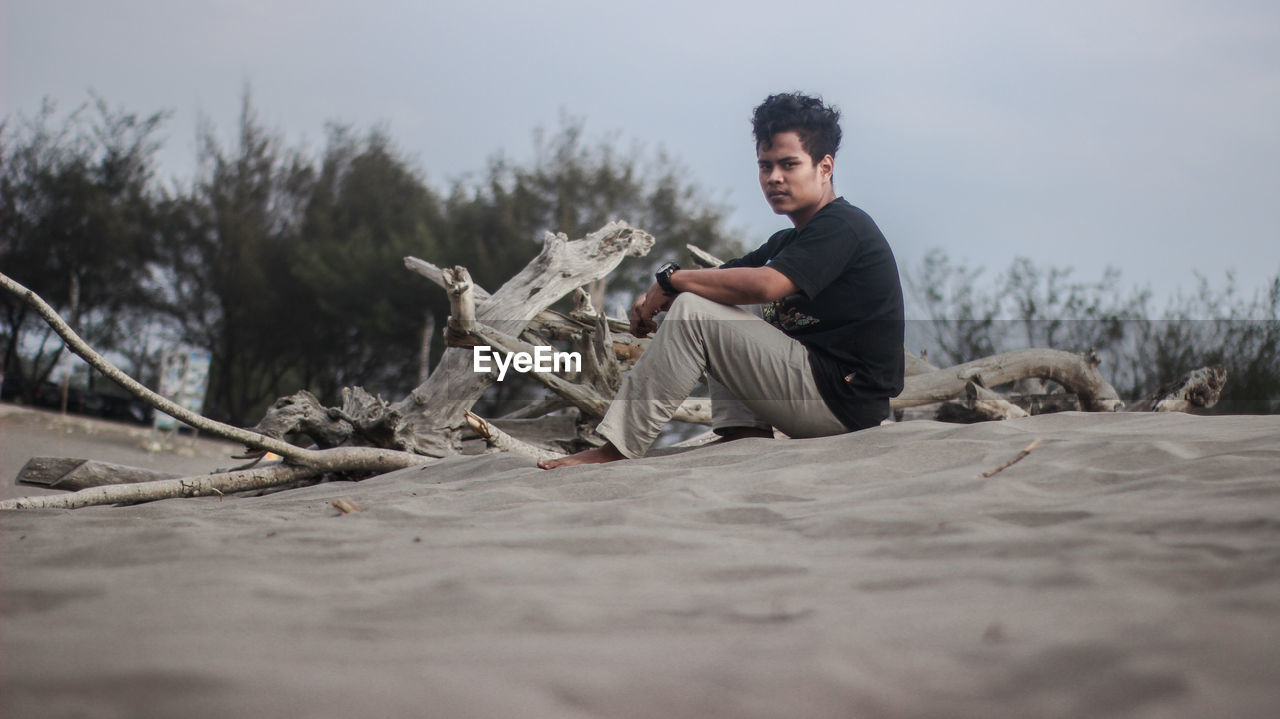 Portrait of young man sitting at beach