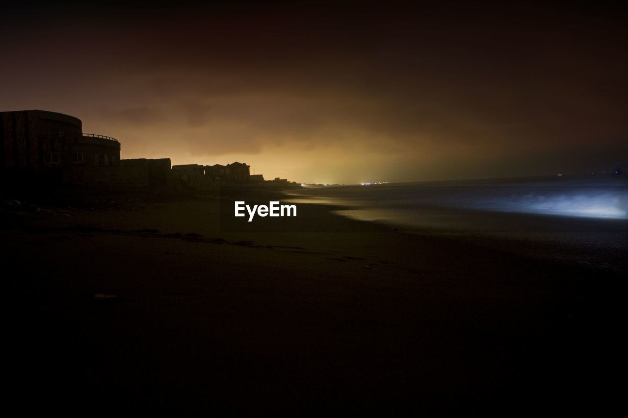 SCENIC VIEW OF CALM BEACH AGAINST SKY DURING SUNSET