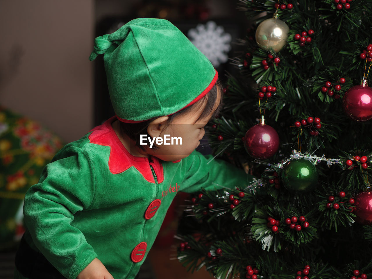 Cute baby girl by christmas tree at home